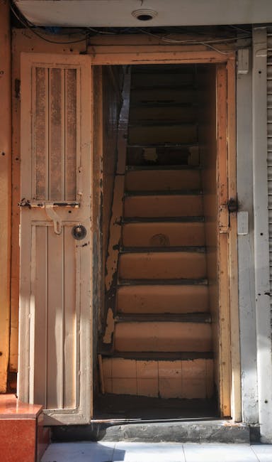 A narrow, indoor staircase with six wooden steps leading upward, enclosed by wooden framing and walls. The stairs are uncarpeted, showing visible wear and darkened edges. To the left of the staircase,