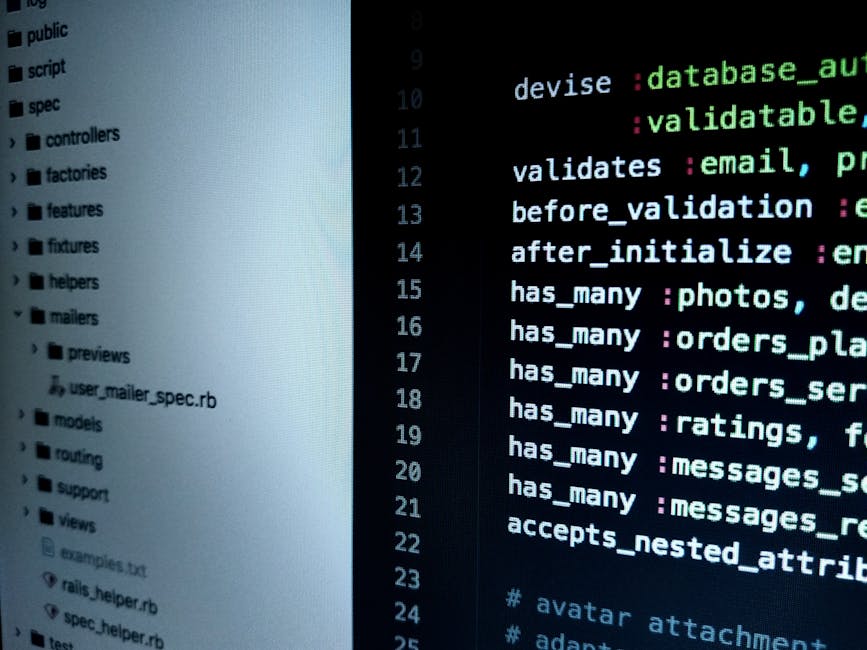 A close-up of a laptop on a desk displaying lines of code in a text editor, with visible HTML and CSS syntax, alongside a large orange digital calculator with black and white buttons. The laptop appea